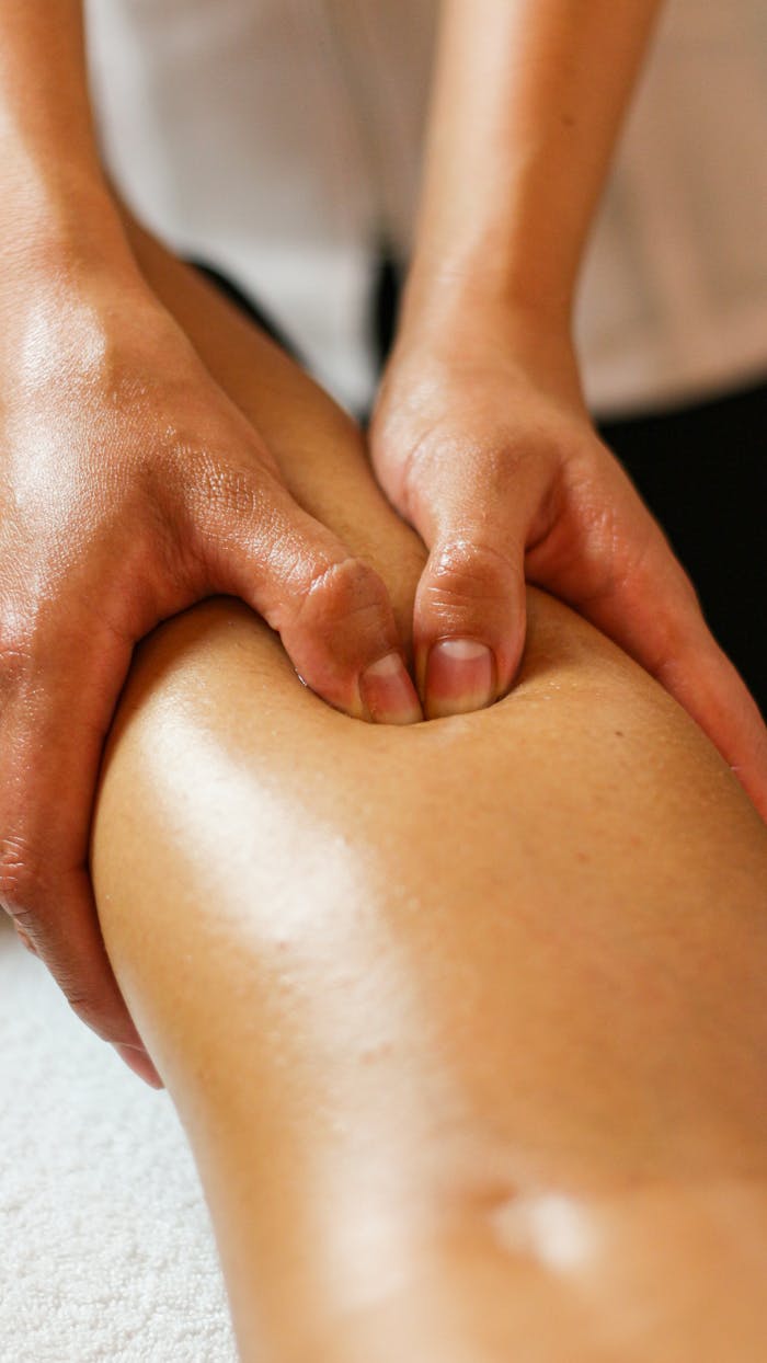 Close-up of hands applying pressure on a leg during a therapeutic massage session.